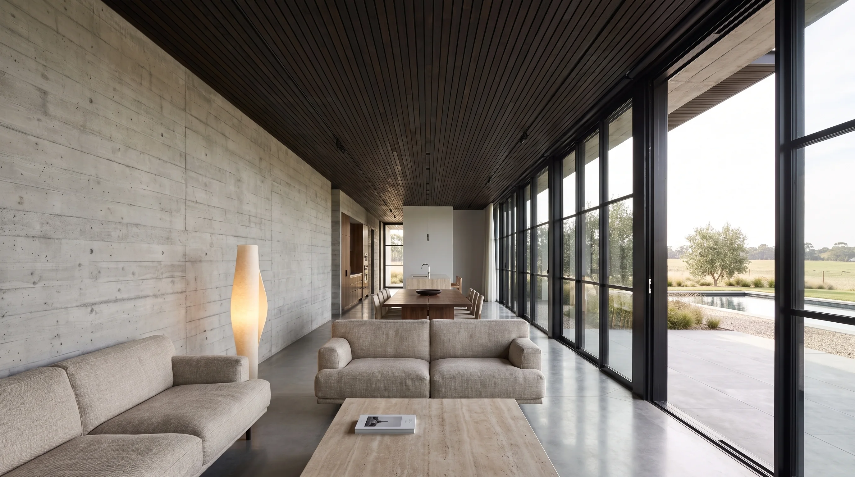Living room of the house with a board-formed concrete wall, timber ceiling and full-height glazing onto the pool